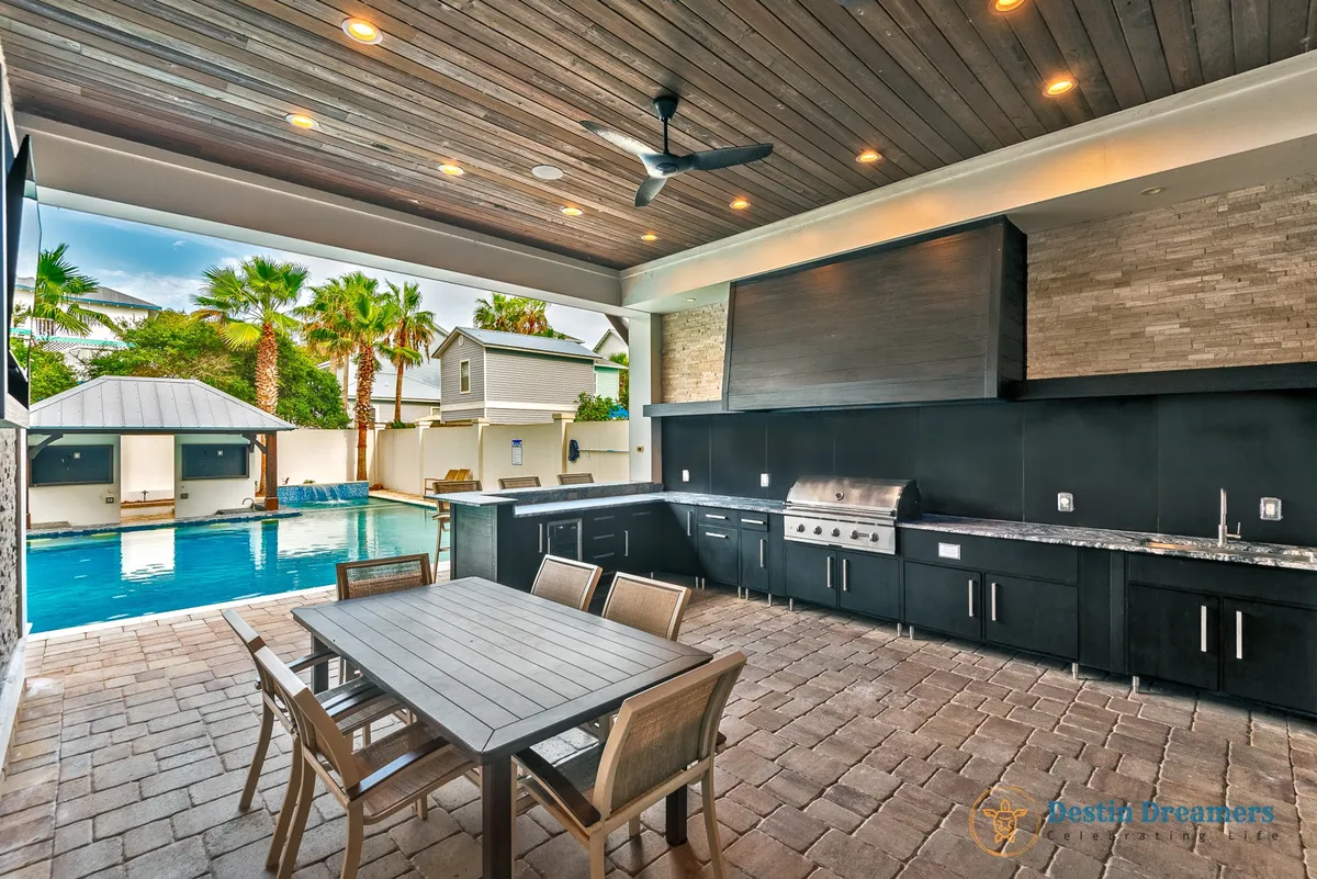 The image features a sparkling private pool, an outdoor kitchen area with a dining table, and inviting lounge space for poolside gatherings. This setup encourages grilling lunches, relaxing after beach outings, and enjoying group fun in a luxurious and comfortable setting.
