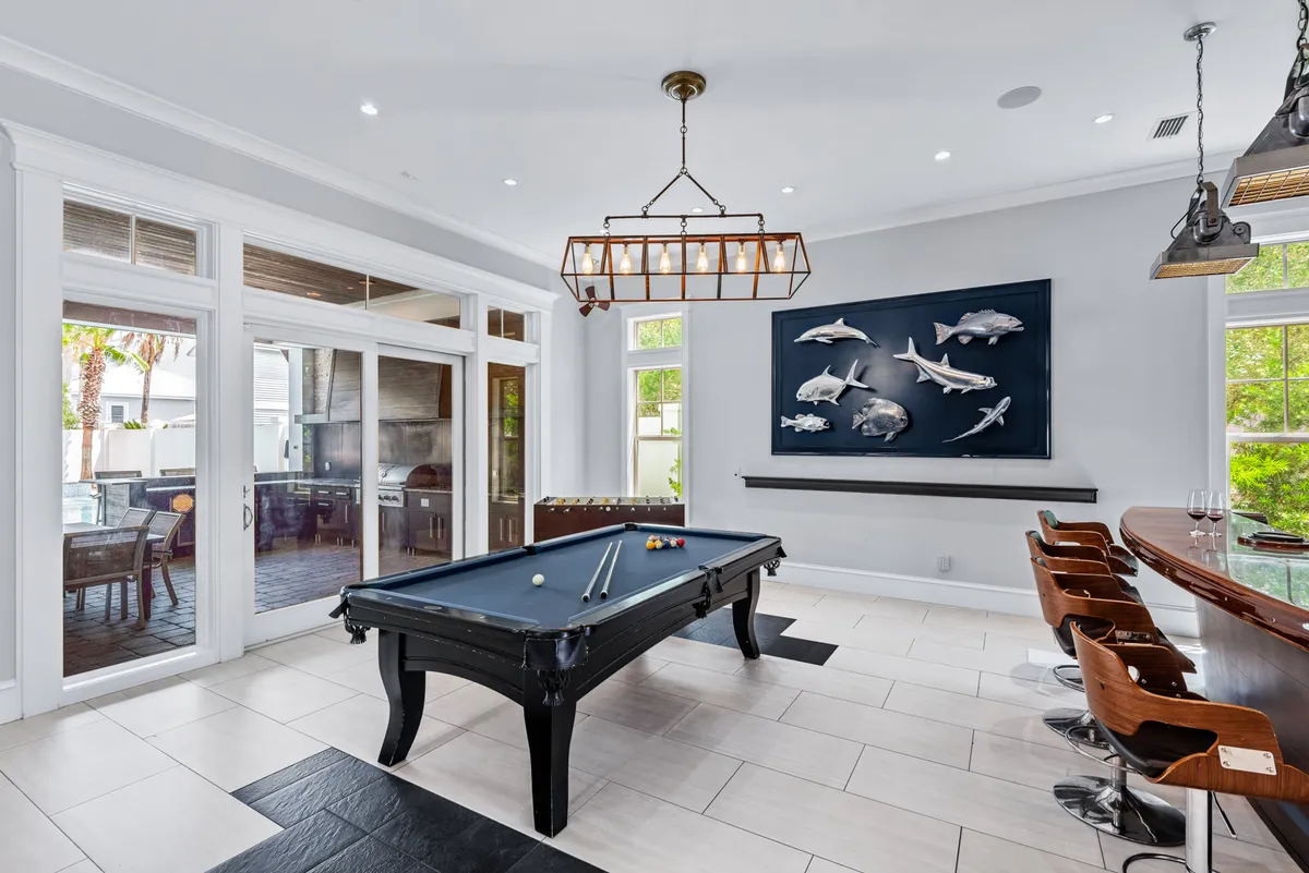 An interior shot of a cozy game room featuring a pool table, bar area, and ocean-themed wall art. The relaxed atmosphere invites guests to unwind, socialize, and enjoy memorable evenings indoors.