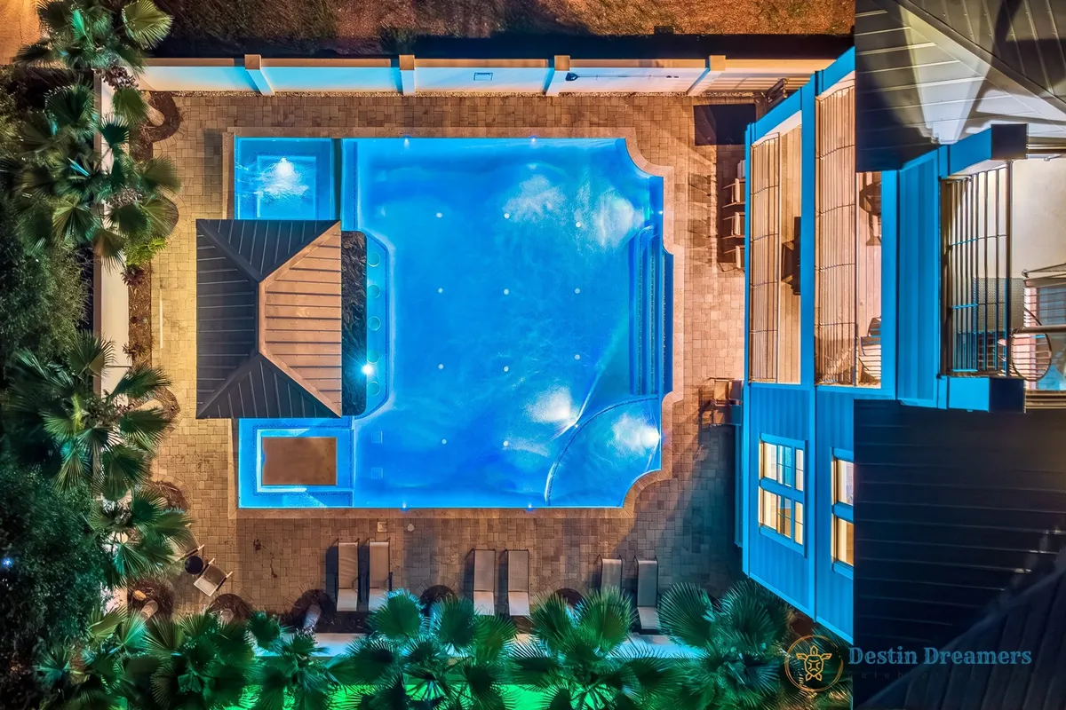 A serene backyard showcases a sparkling swimming pool surrounded by palm trees, a stylish gazebo, and comfortable lounge chairs. The inviting outdoor area is perfect for relaxation and group gatherings, with ample space for pets to enjoy the fresh air alongside their owners.