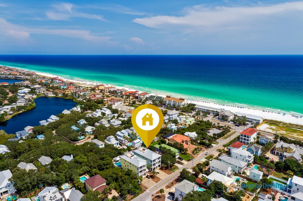 A sweeping aerial shot marks The Life Aquatic property with a yellow icon, set amidst a cluster of beach homes, lush trees, and the sparkling turquoise Gulf of Mexico coastline. The white sand beach and surrounding neighborhood highlight proximity to both natural beauty and local attractions.